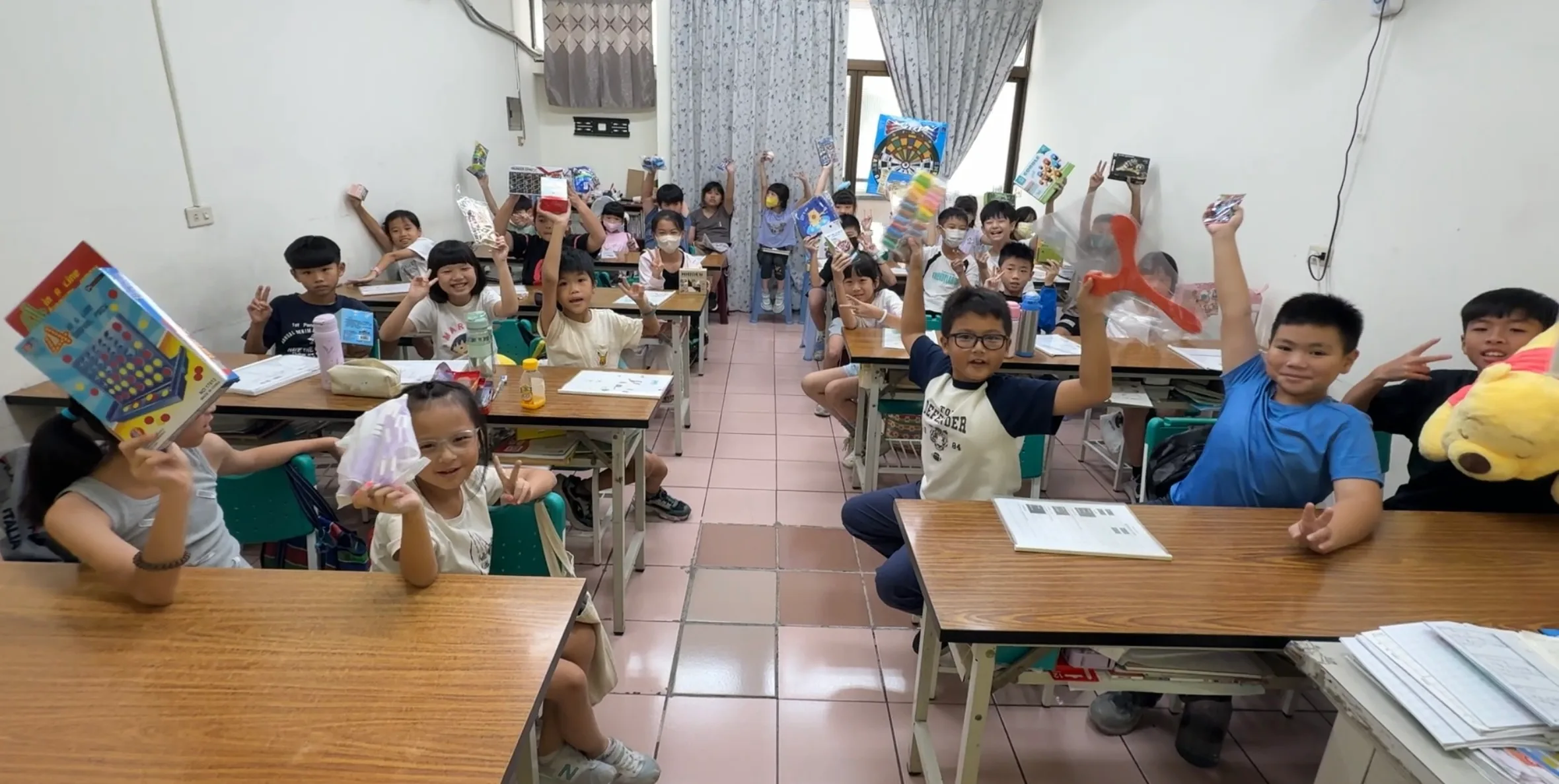 教室裡全班孩子舉著書和玩具開心合照