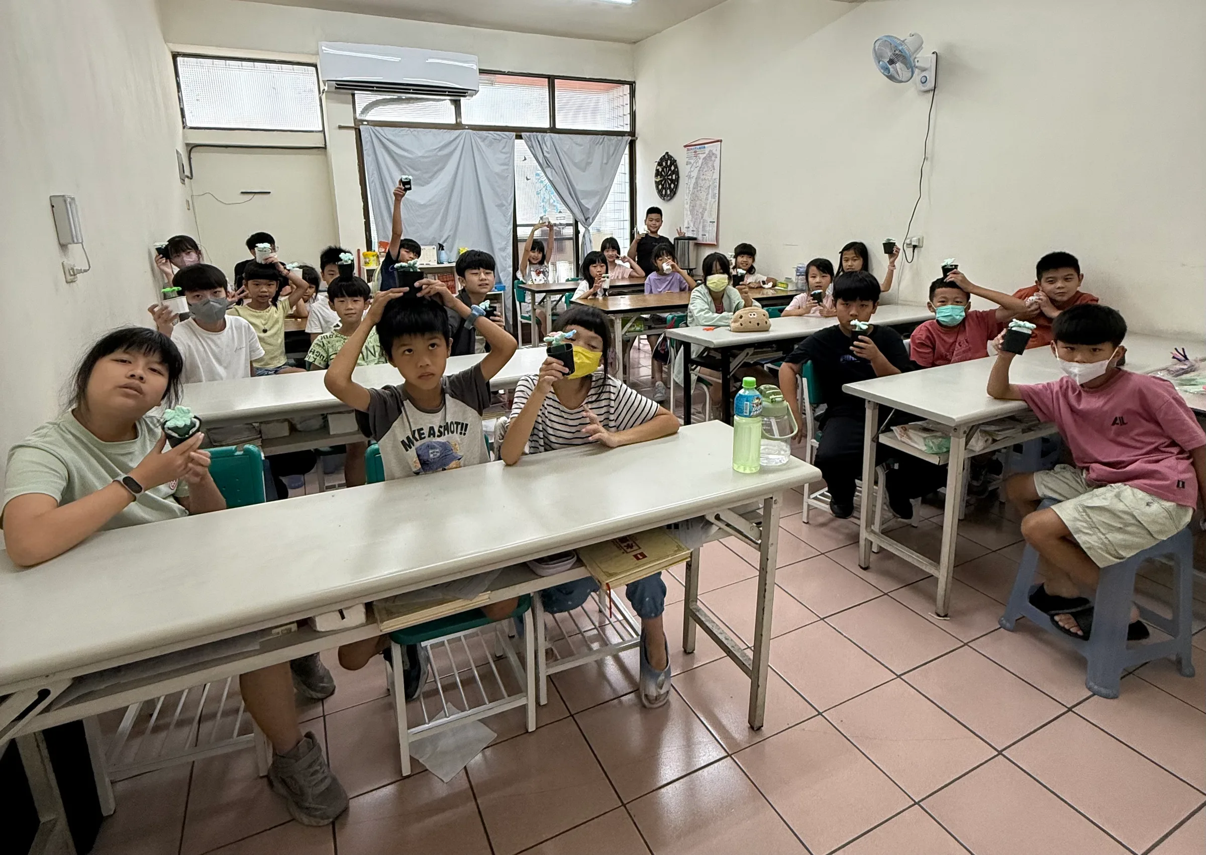 教室裡,孩子們舉著自己做的小盆栽