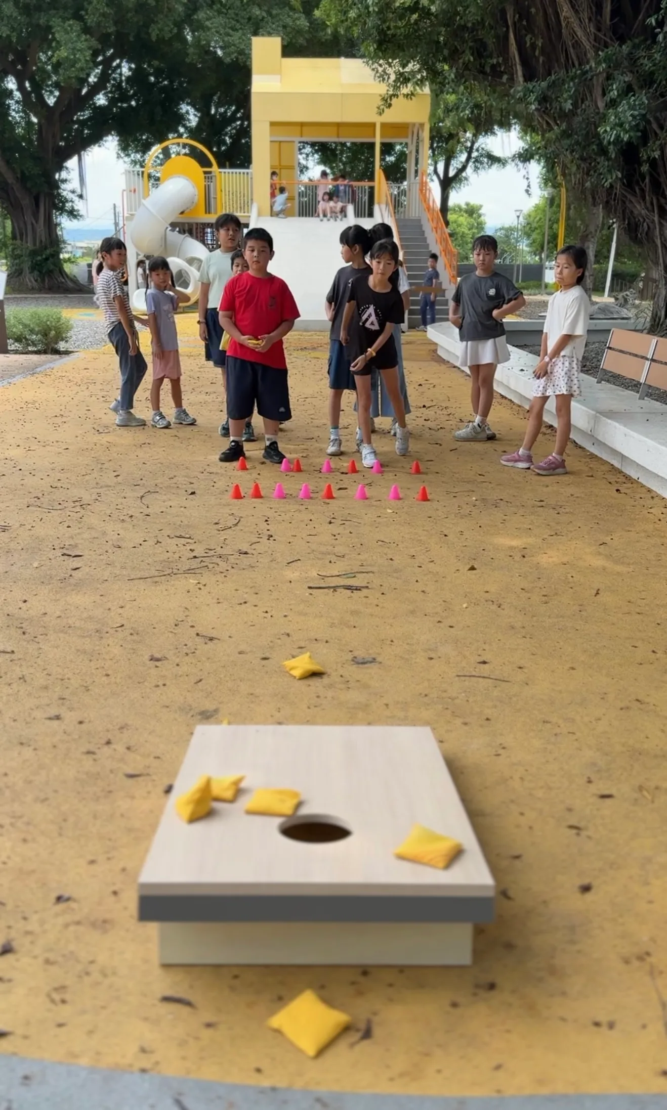 公園裡玩丟沙包遊戲,孩子們站在遠處排隊